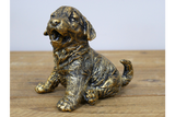 Bronze statue of a puppy on a wooden surface with a light gray background