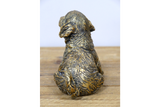Bronze statue of a dog on a wooden surface with a white background