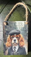 Decorative sign with a Cavalier King Charles dog wearing a hat and suit.
